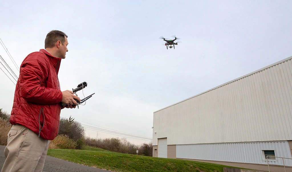 Travelers employee flying drone above building.