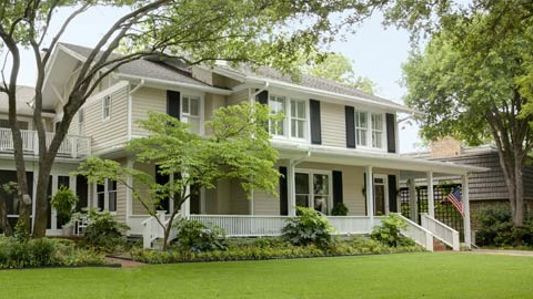 Front of a house with a large tree in front of it.