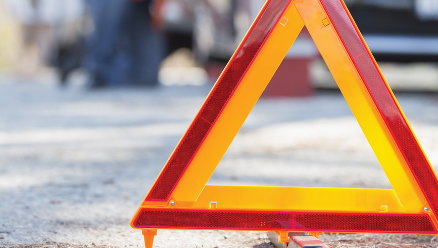 Triangle reflection on road in front of a truck accident.