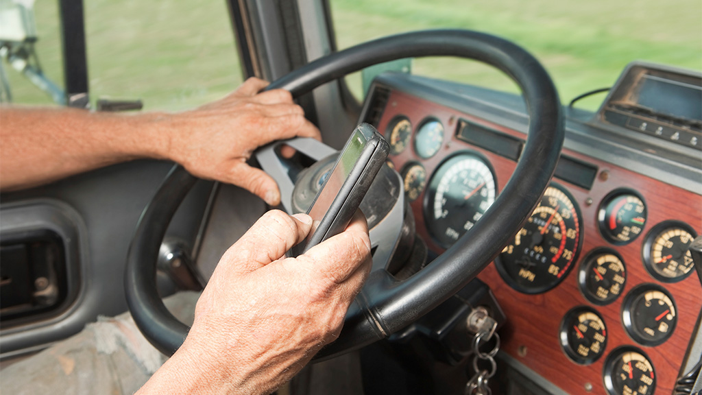 zoomed in shot of truck driver with phone in hand while behind the wheel