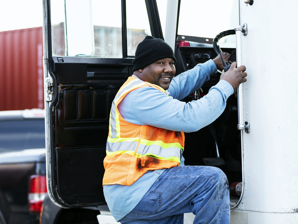 Truck driver smiling and climbing into cabin.