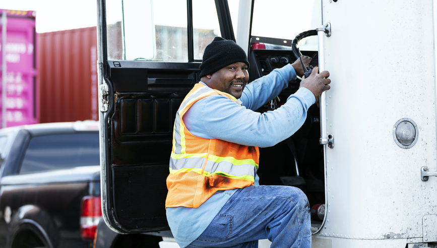 Truck driver smiling and climbing into cabin.