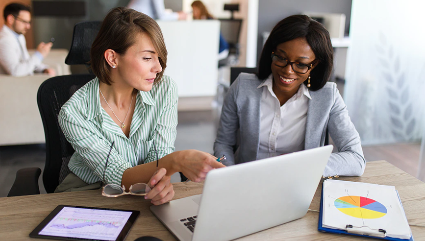 Two business women looking at a laptop talking.