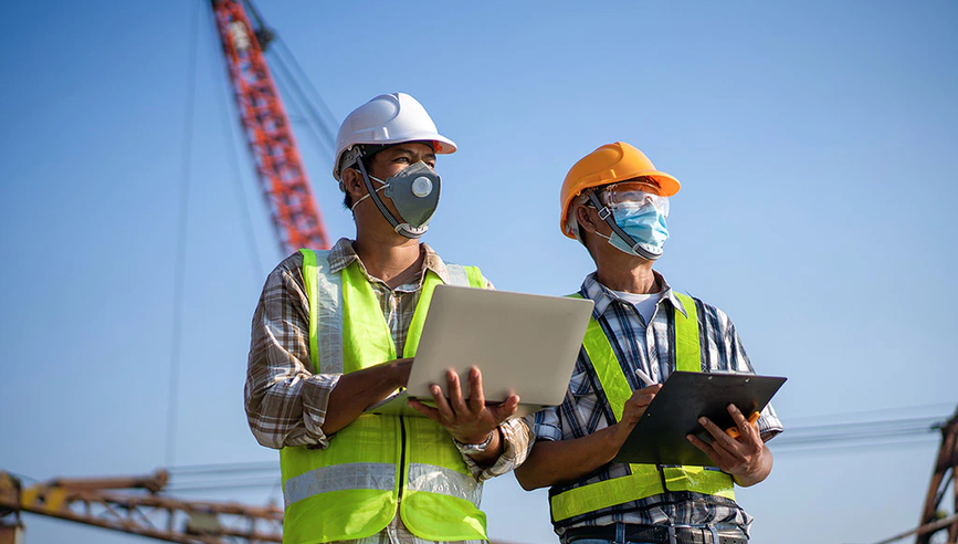 Two construction employees supervise the work.