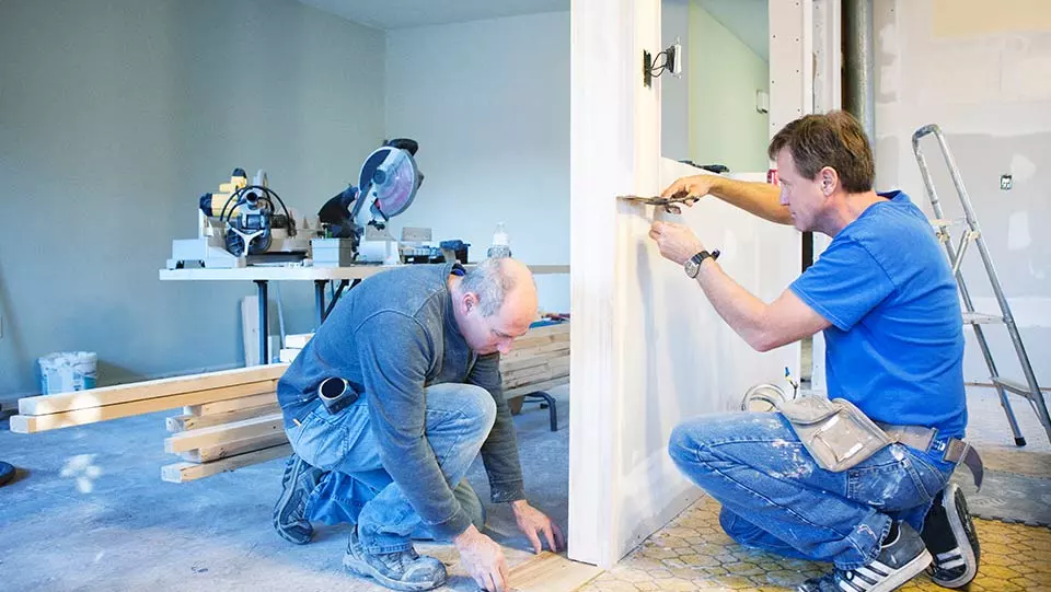 Two contractors working on kitchen in house.