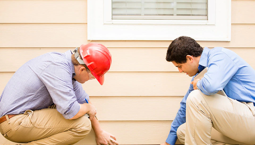 Two men looking at house as part of disaster recovery.