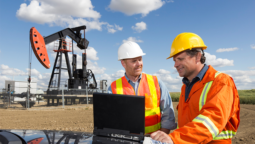 Two oil workers receive training onsite at an oil field.