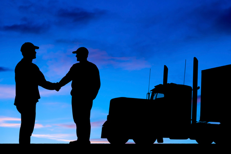 Two truck drivers shaking hands at dawn