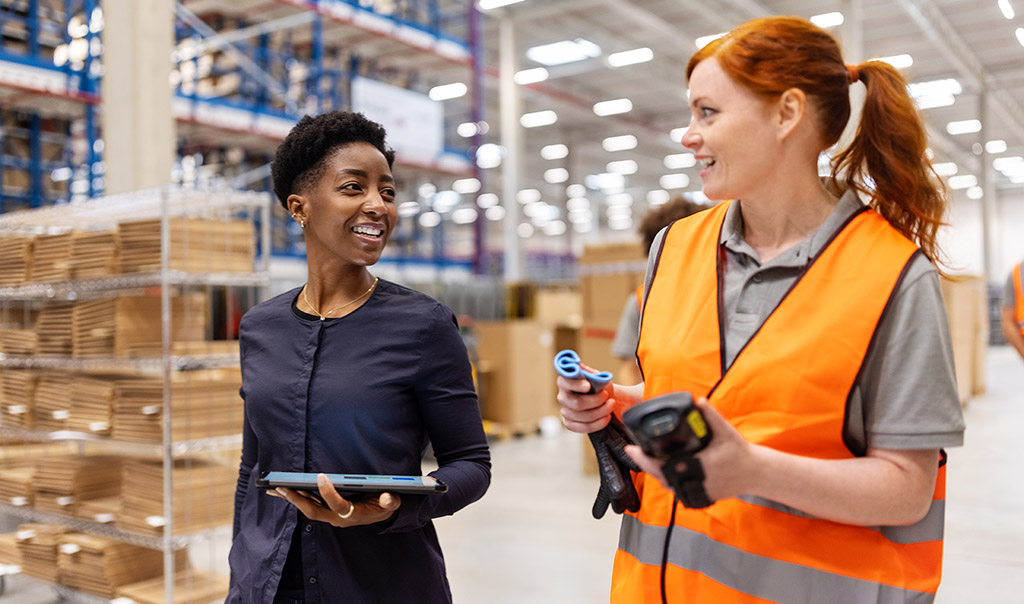 Two employees walking in a warehouse, having a discussion.