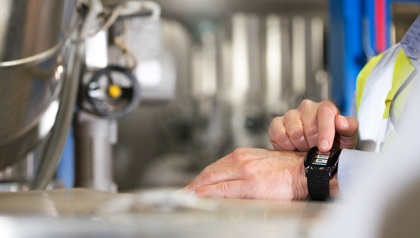 Person pressing a button on a wearable device around their wrist.