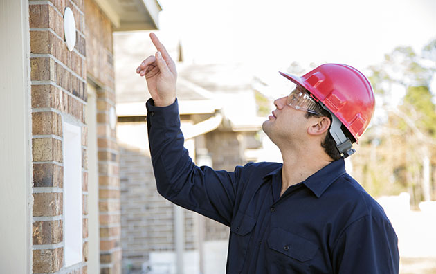 Home inspector pointing his finger and inspecting the roof of a house