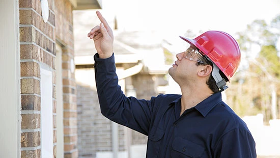Home inspector pointing his finger and inspecting the roof of a house.