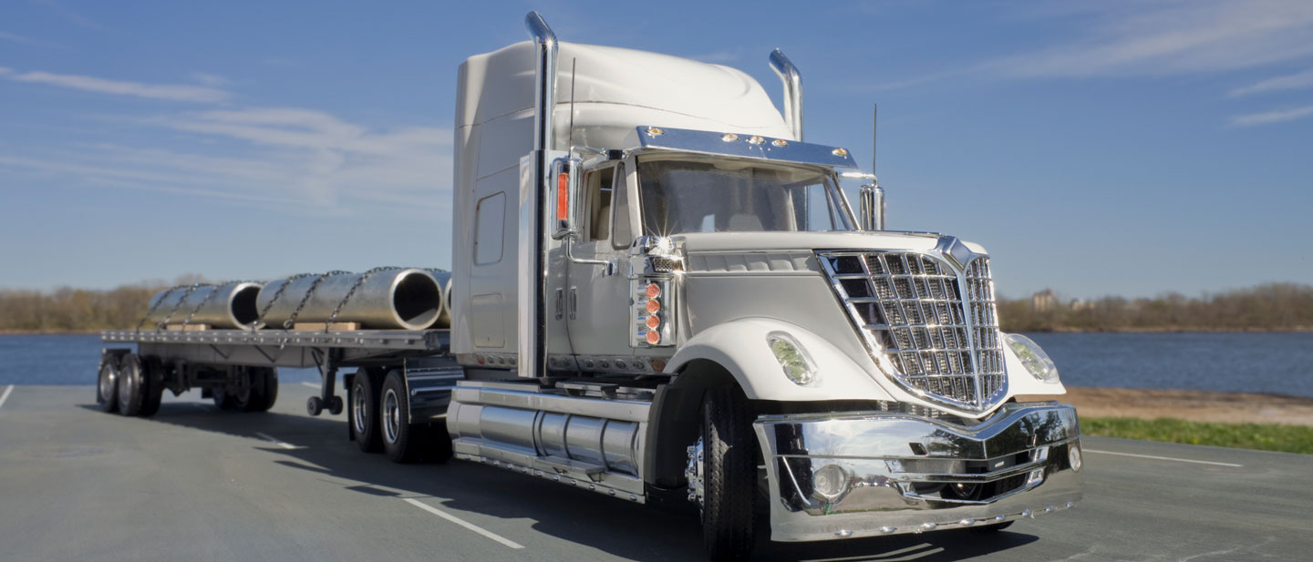 White truck hauling metal cargo on a remote road.