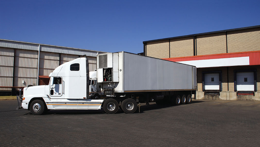 white large commercial truck unloading cargo in a parking lot