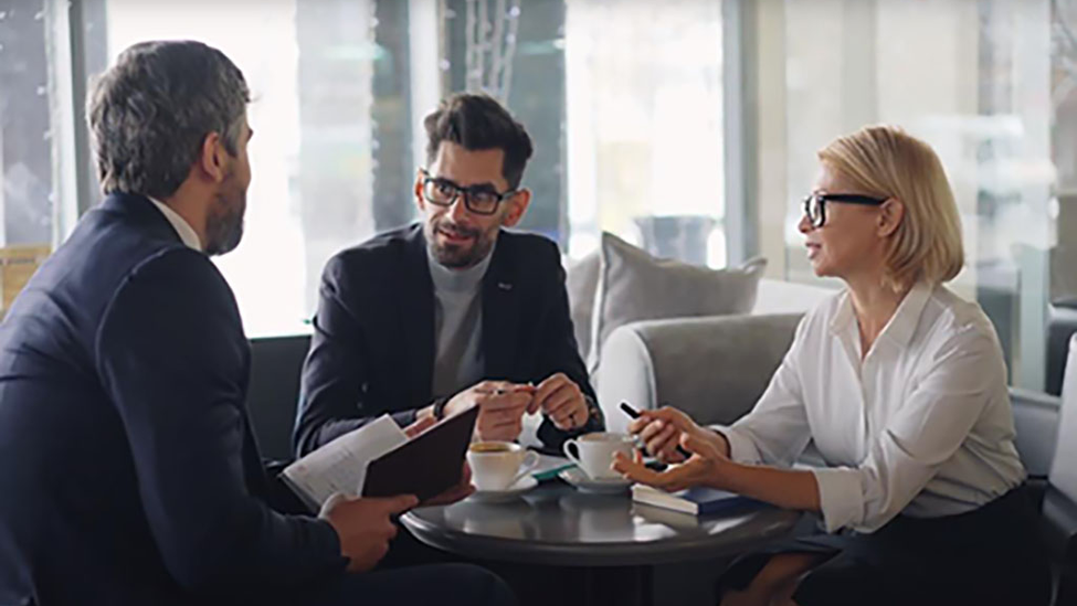 Three small business owners sitting around a coffee shop table discussing their business.