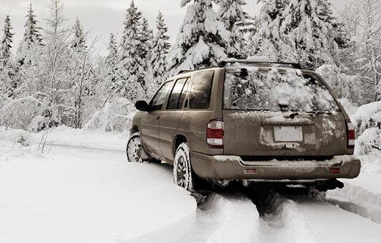 Grey SUV driving in snow.