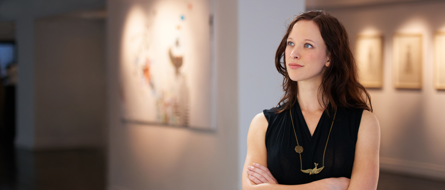 A woman looking at wall art in a museum.