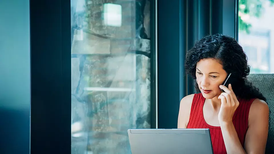 Woman at desk using a cell phone.