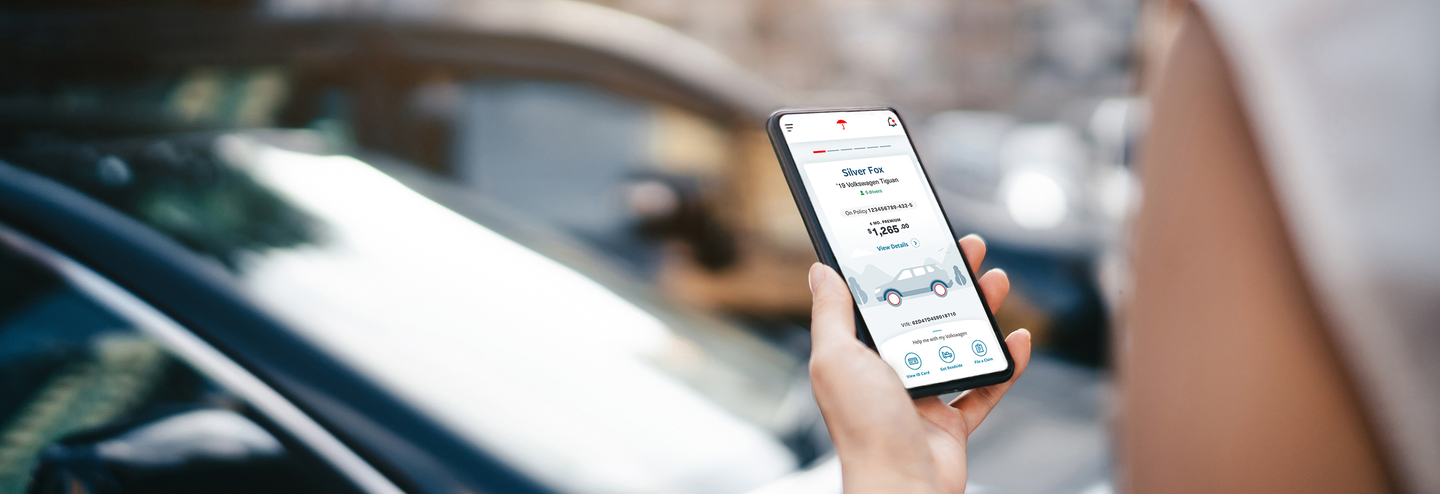 Woman holding mobile phone displaying MyTravelers app, car in background.