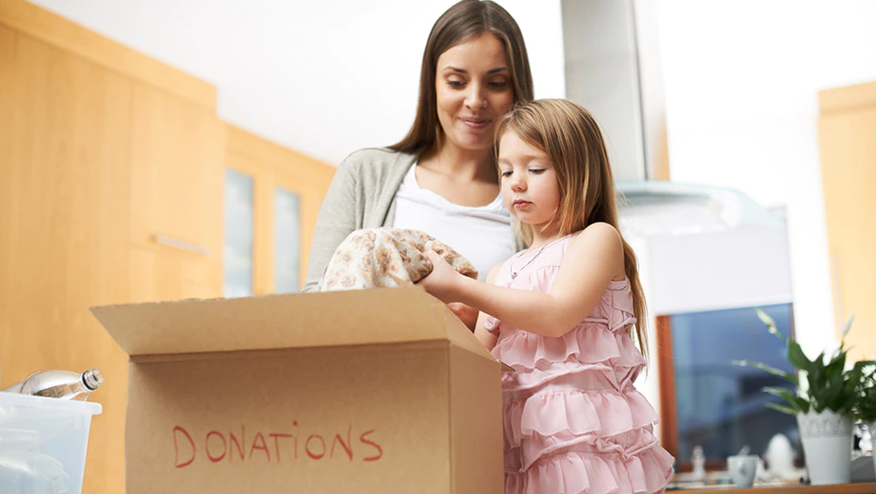 Woman declutter house by putting content in boxes with daughter.