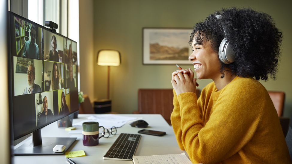 Businesswoman with headphones smiling during video conference. Multiracial male and female professionals are attending online meeting. They are discussing business strategy.