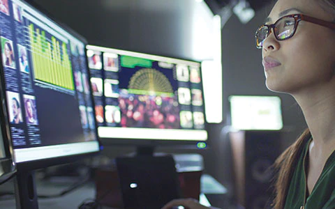 Woman in front of computer panels.