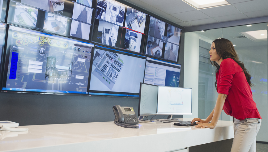 Woman in red top reviewing a screen of camera surveillance.