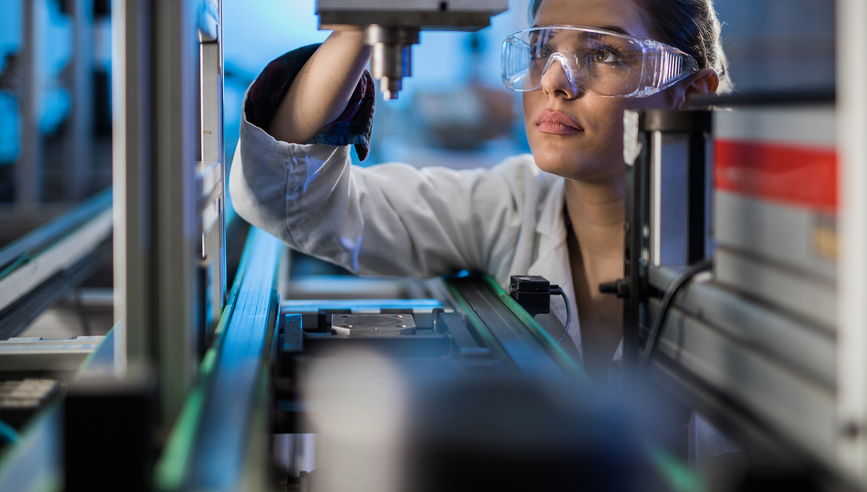 Quality control worker analyzing machine part on a manufacturing machine