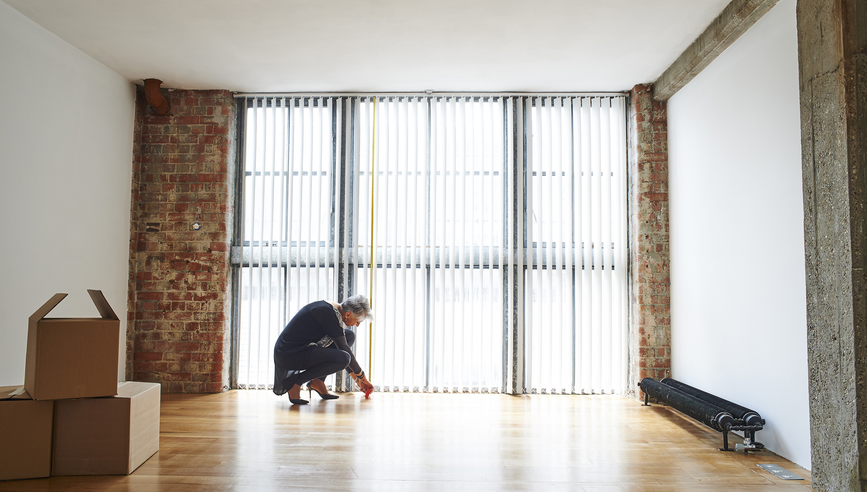 Woman measuring room when preparing to downsize home.