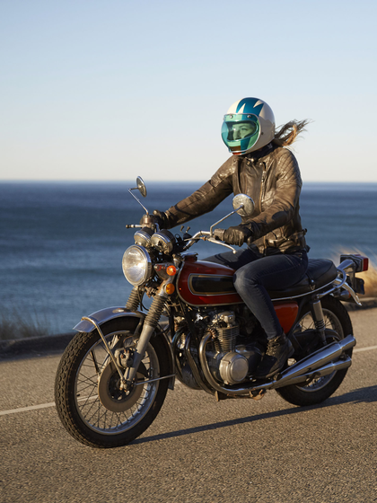 Person riding a motorcycle on a road next to the ocean.