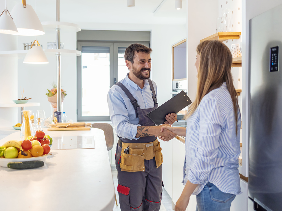 A contractor shaking hands with a homeowner in a kitchen.