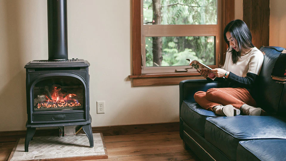 Woman sitting on sofa in front of a pellet stove.