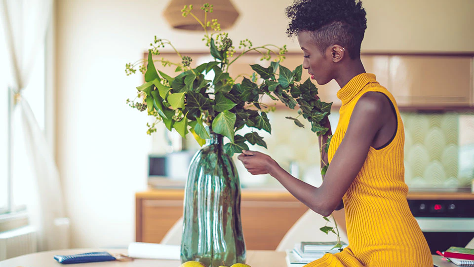 Woman arranging flowers in a vase in a kitchen.