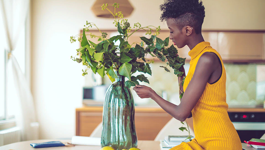 woman arranging flowers in a vase in kitchen.