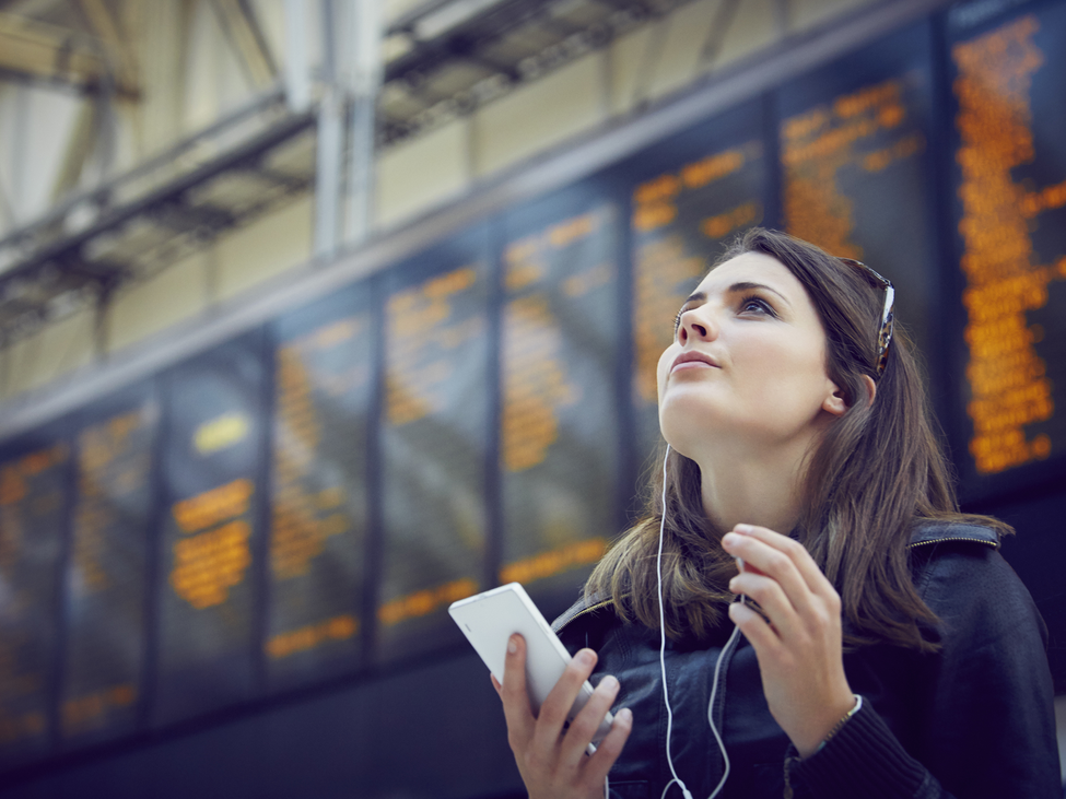 A woman looks up at an arrival/departure transportation information board.