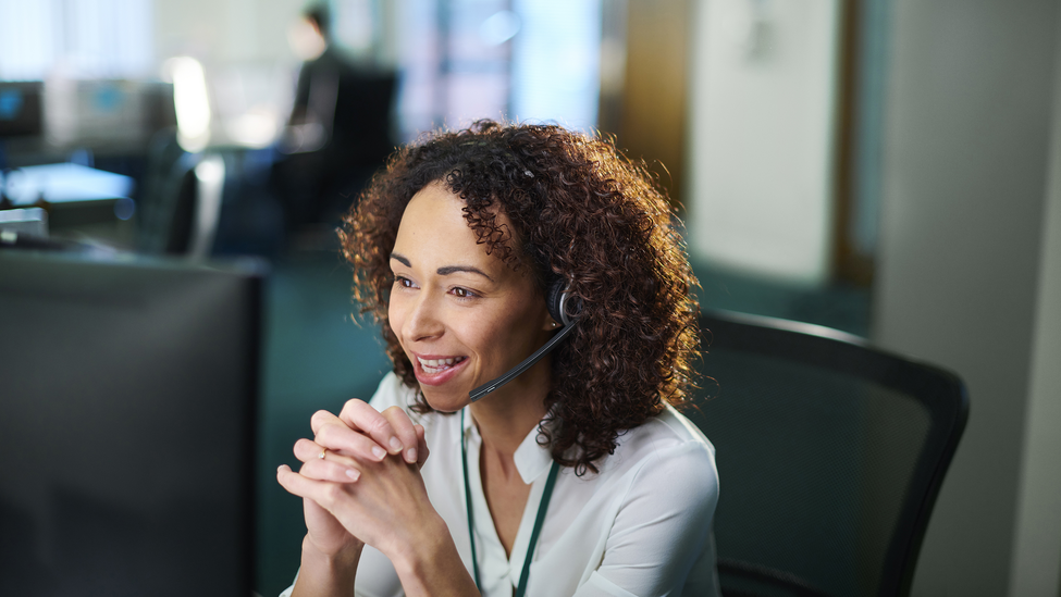 A woman talks on the telephone using a headset.