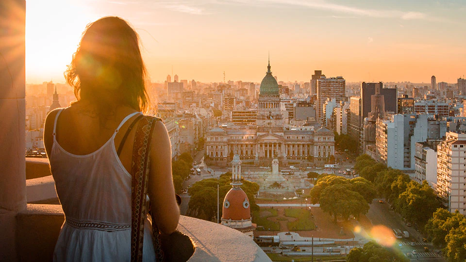 Woman traveling safely alone looking at city during sunset.