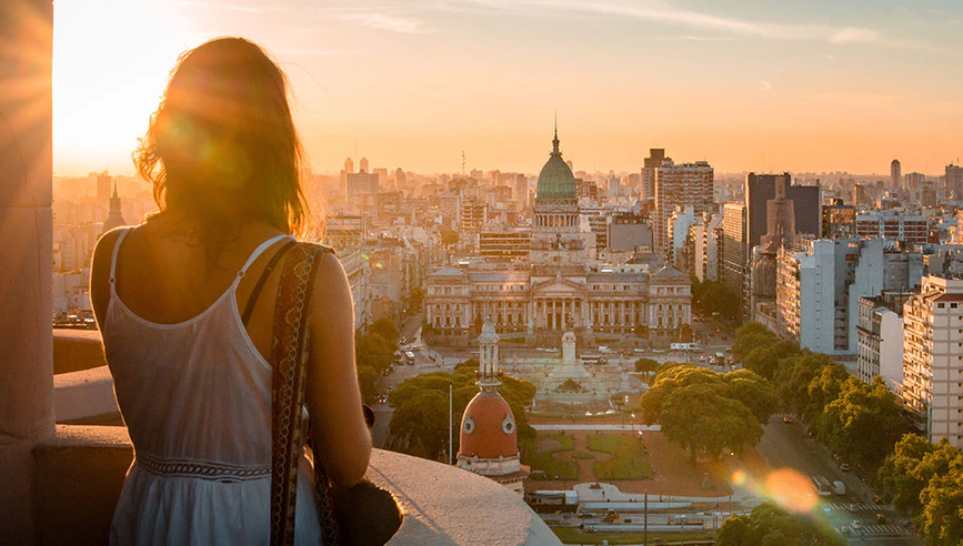 Woman traveling safely alone looking at city during sunset.