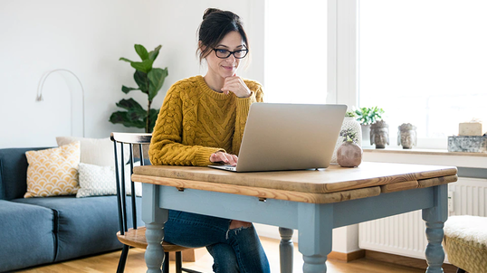 Woman working at her home desk on a laptop.