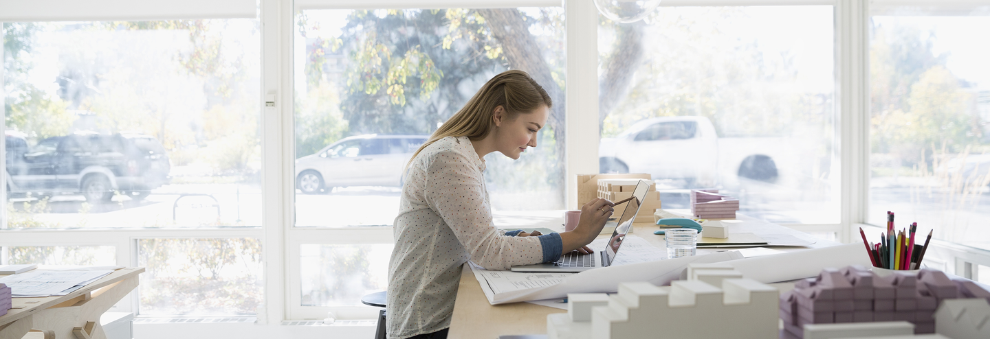 A woman works at a laptop in an office.