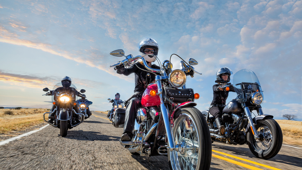 A group of motorcycle riders on an open road highway.