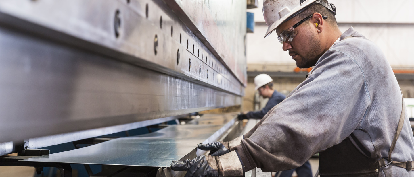 Machinist in hard hat working in factory.