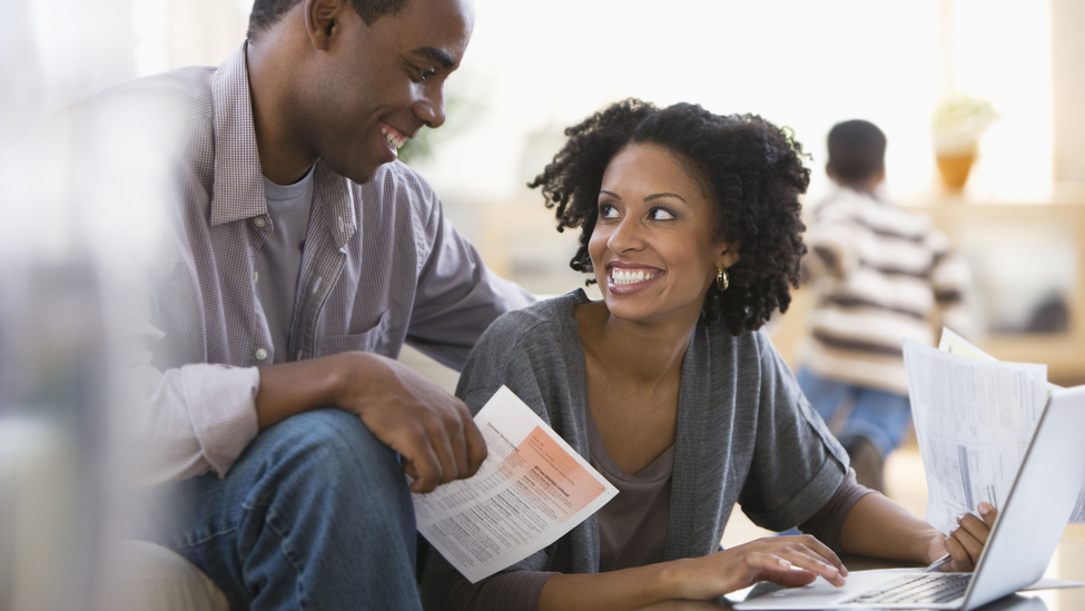 young African American couple paying bills at a laptop