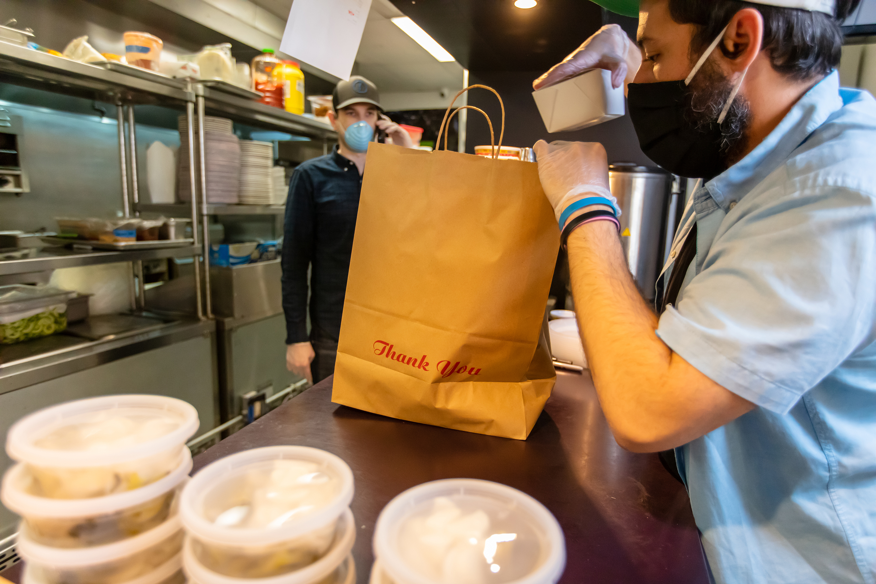 Young man packing a food order at a restaurant.
