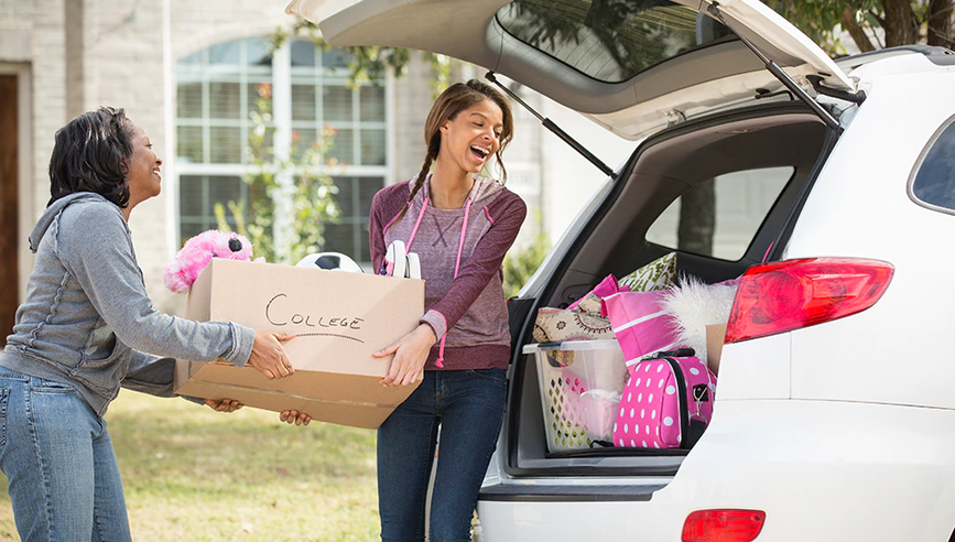 Young woman and her mom packing boxes into a car, heading off to college.